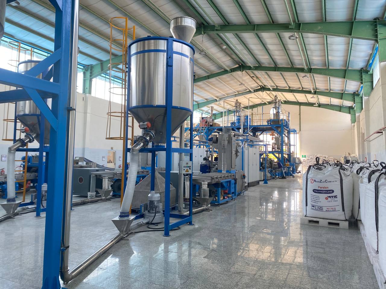 The Polyazin compounding hall — stainless mixing hoppers and extrusion lines under daylight