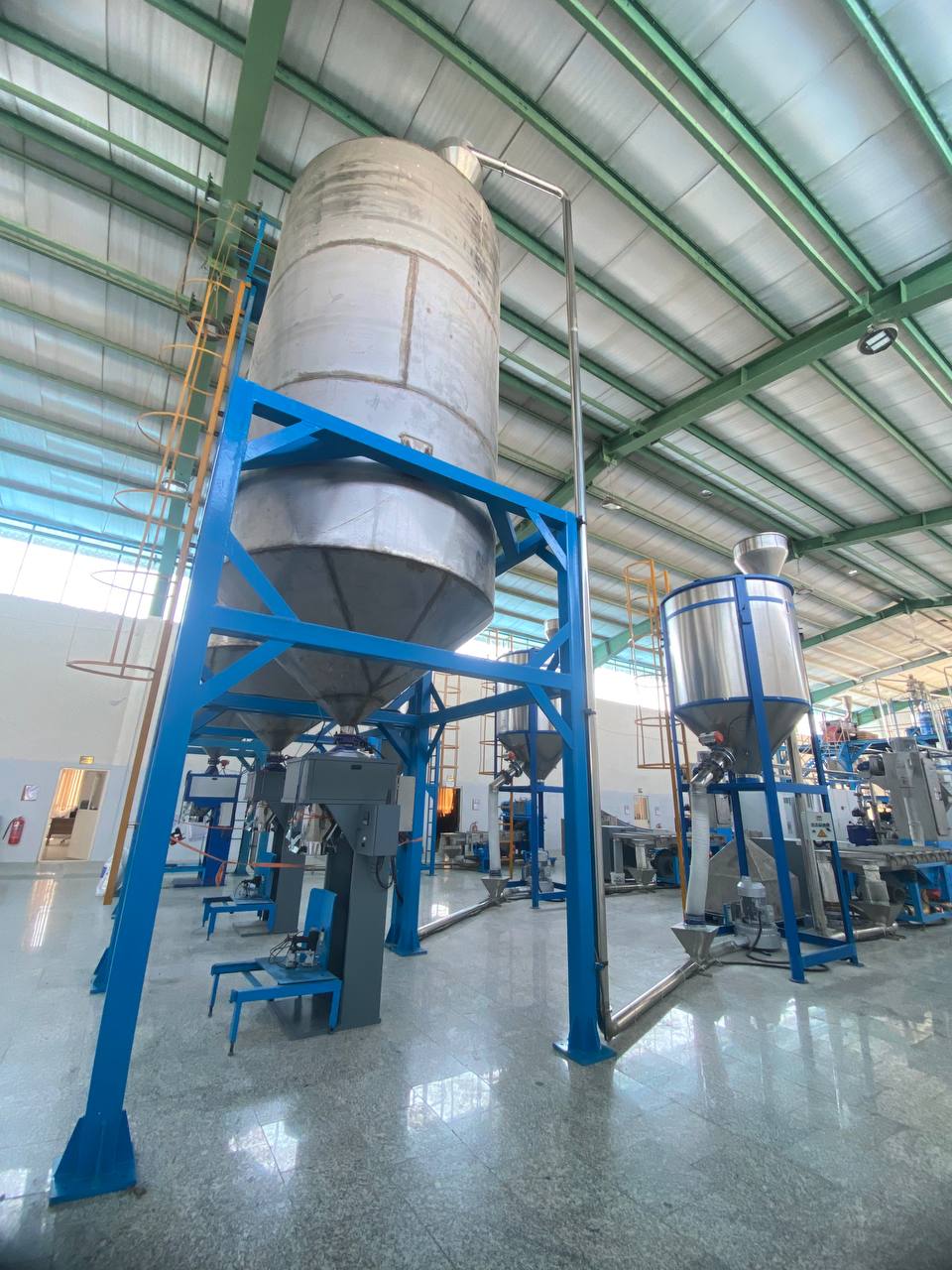 Stainless storage silo feeding the bagging station on its blue steel frame