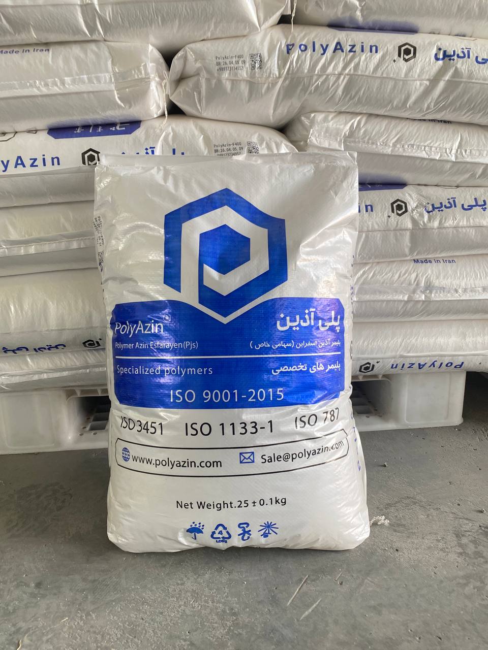 A branded PolyAzin 25 kg bag with printed batch number, QR code and ISO standards, in front of stacked pallets in the warehouse