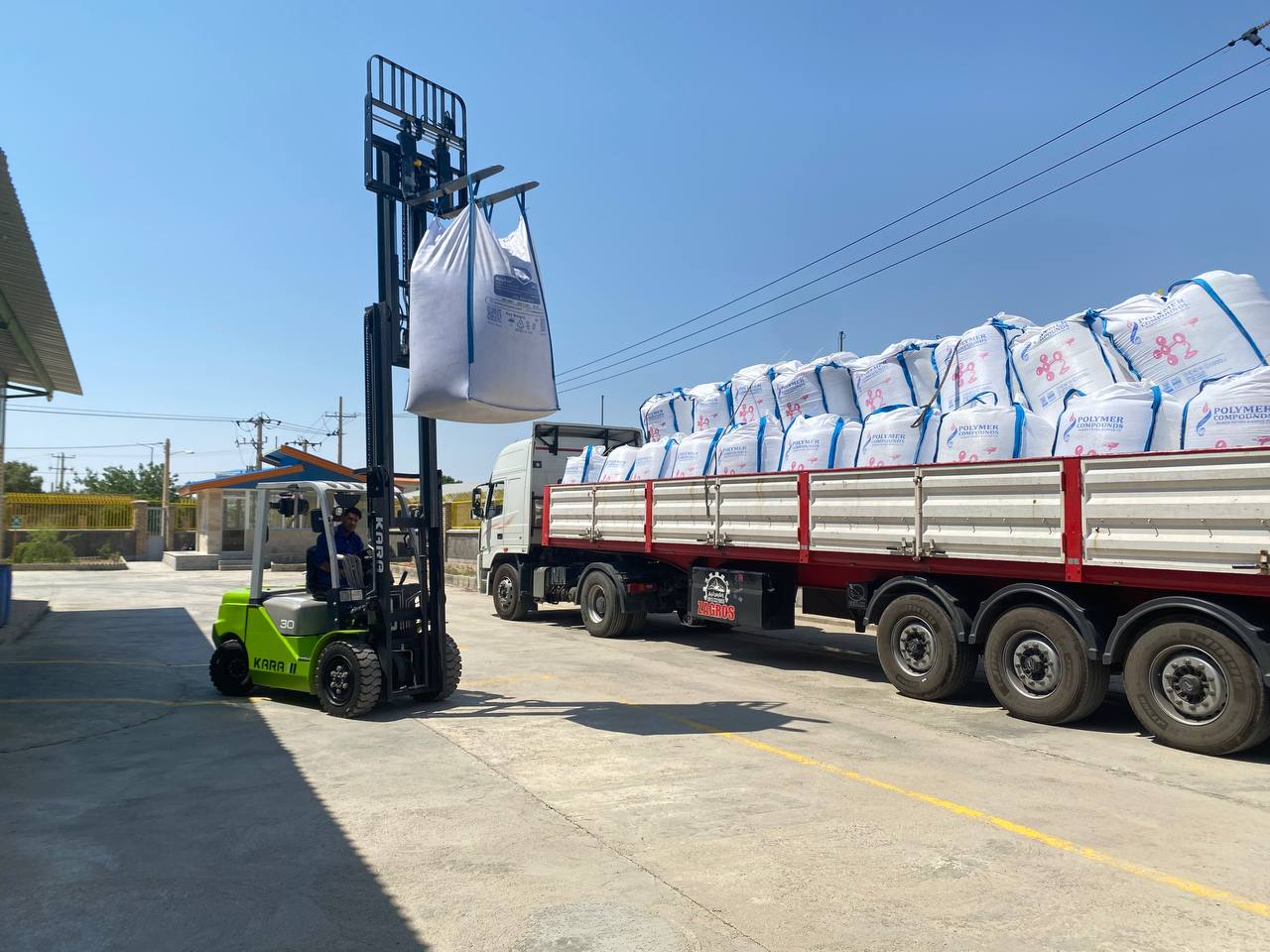 Forklift loading PolyAzin big-bags onto a flatbed truck at the plant gate