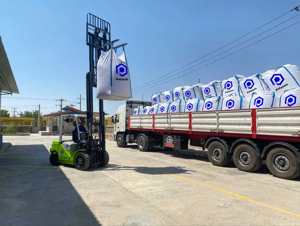 Forklift loading PolyAzin big-bags onto a flatbed truck at the plant gate